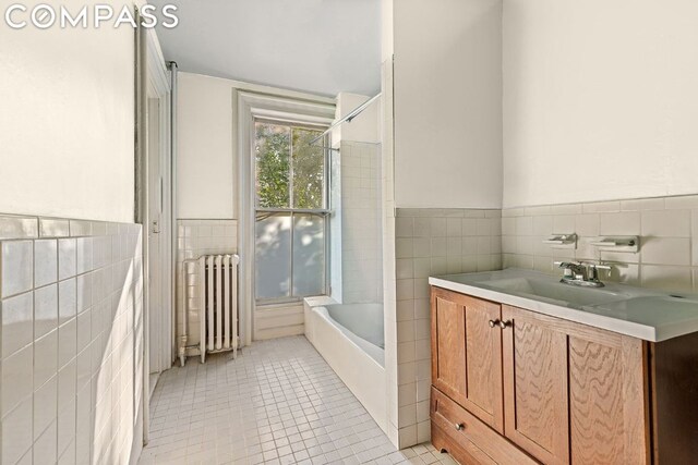 bathroom with radiator, tile walls, vanity, and tile patterned floors