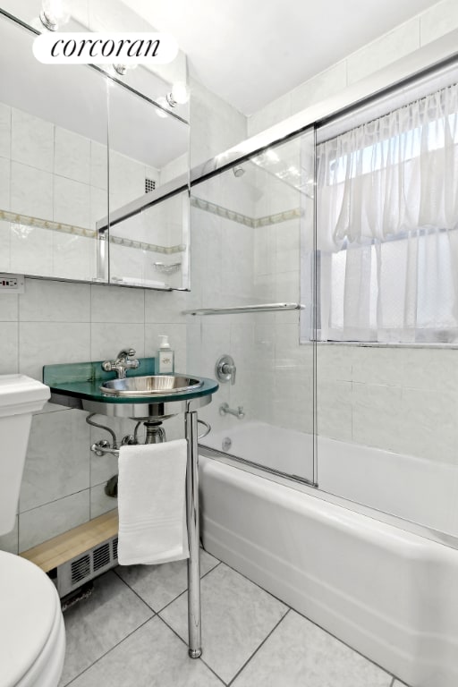 bathroom with combined bath / shower with glass door, tile walls, toilet, and tile patterned flooring