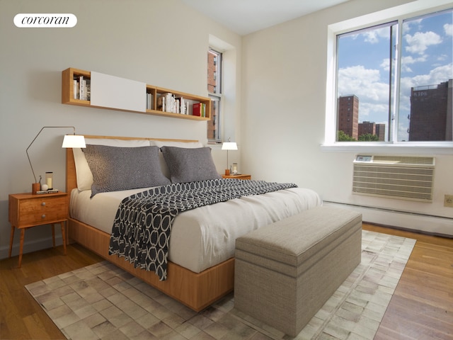 bedroom with multiple windows, a baseboard heating unit, and wood finished floors