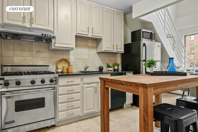 753 E 5th St Unit 4C, New York City, NY 10009 - kitchen featuring appliances with stainless steel finishes, under cabinet range hood, a sink, dark countertops, and backsplash