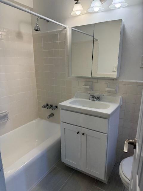 full bathroom with tile walls, shower / bath combination, toilet, vanity, and tile patterned floors