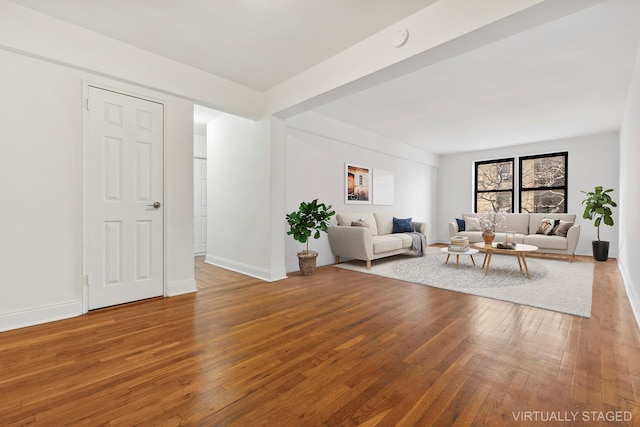 unfurnished living room featuring hardwood / wood-style flooring and baseboards