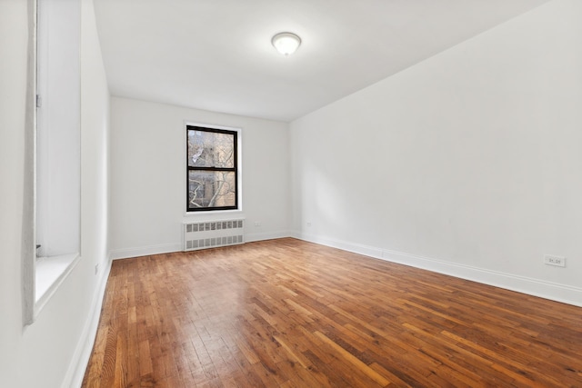 spare room featuring radiator, baseboards, and hardwood / wood-style floors