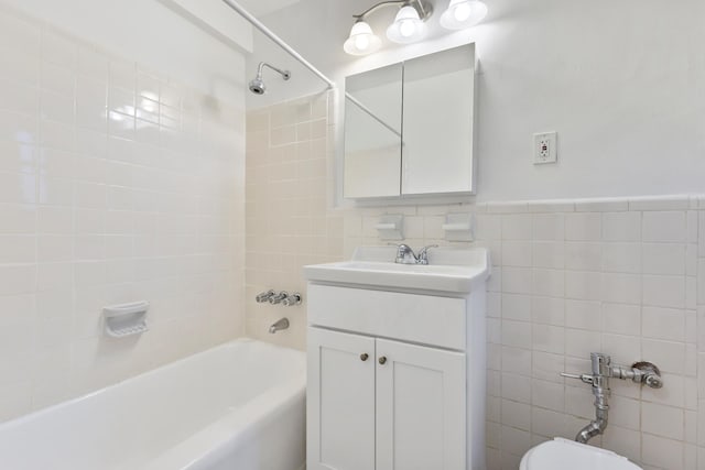 full bath featuring toilet, tile walls, vanity, and bathing tub / shower combination