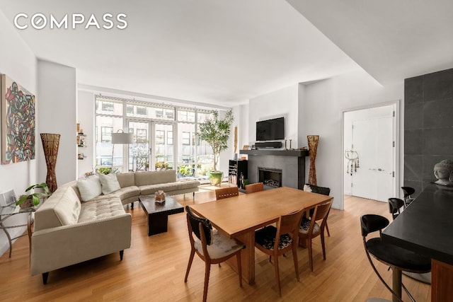 dining space with a tiled fireplace, floor to ceiling windows, and light hardwood / wood-style floors