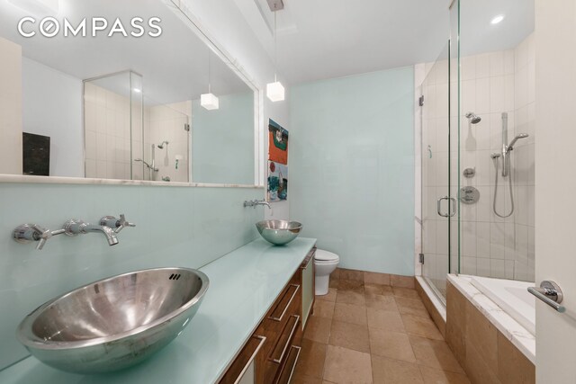 bathroom featuring a stall shower, a sink, toilet, and double vanity