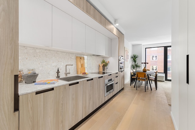 kitchen with stainless steel oven, modern cabinets, and a sink