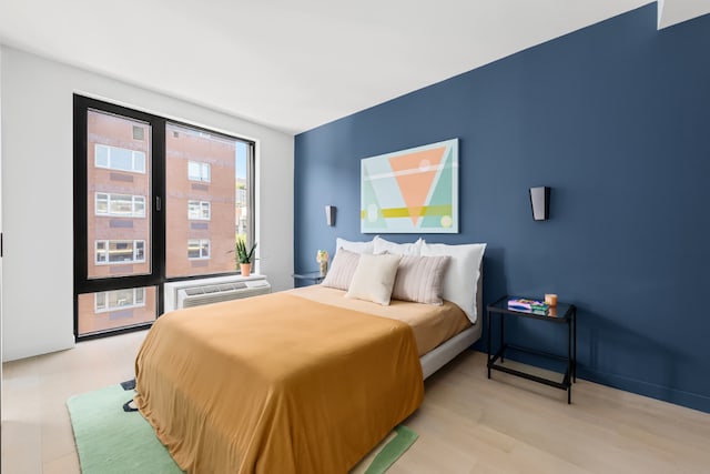 bedroom featuring a wall mounted air conditioner and light hardwood / wood-style floors