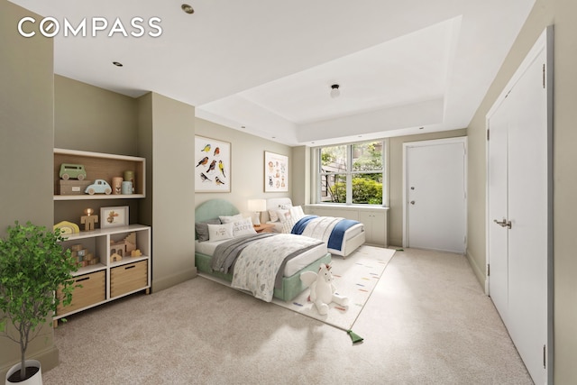 carpeted bedroom with a raised ceiling