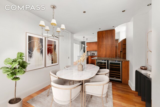 dining room with light wood-style flooring, baseboards, and beverage cooler