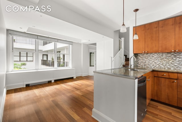 kitchen featuring dishwashing machine, brown cabinetry, a peninsula, and a sink