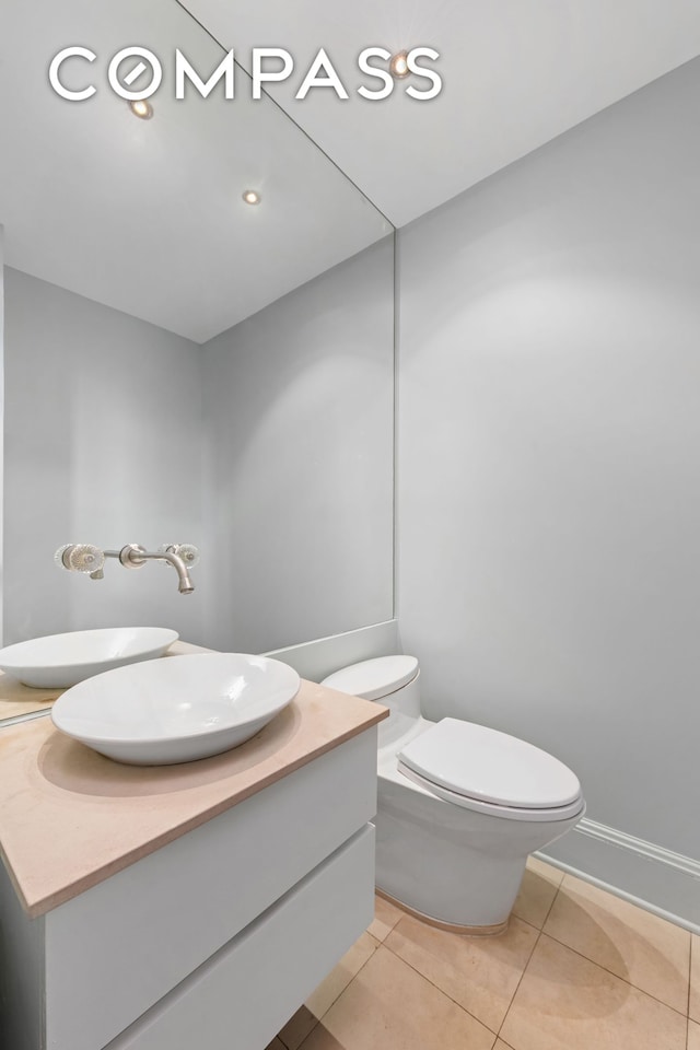 half bath with toilet, recessed lighting, vanity, and tile patterned floors