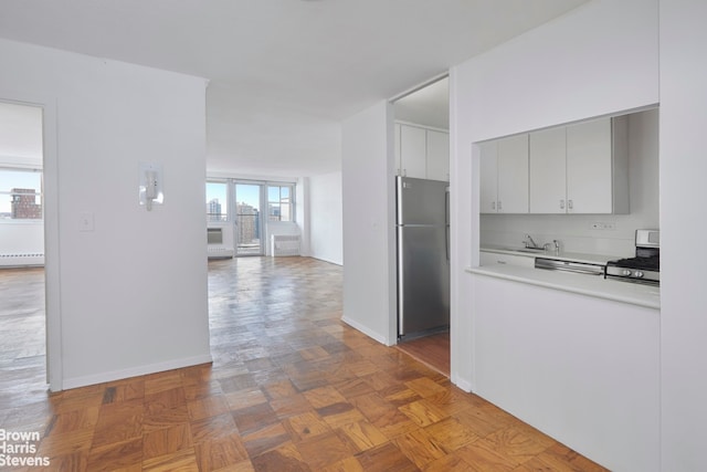 kitchen featuring baseboard heating, sink, stainless steel appliances, and parquet floors