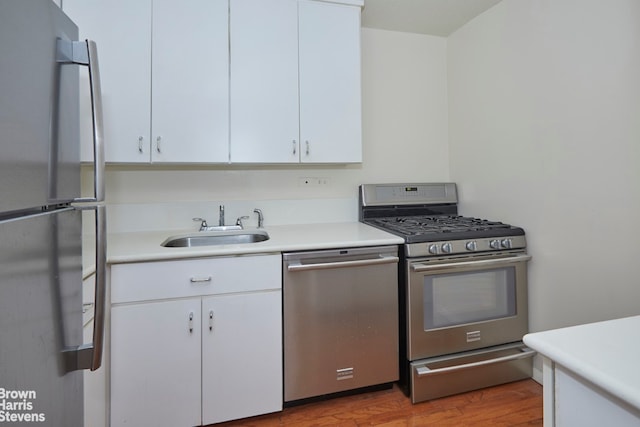 kitchen with white cabinetry, stainless steel appliances, light countertops, and a sink