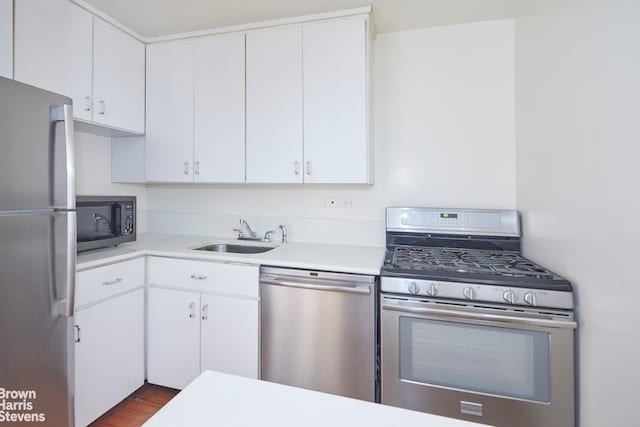 kitchen with dark wood-style floors, a sink, light countertops, white cabinets, and appliances with stainless steel finishes