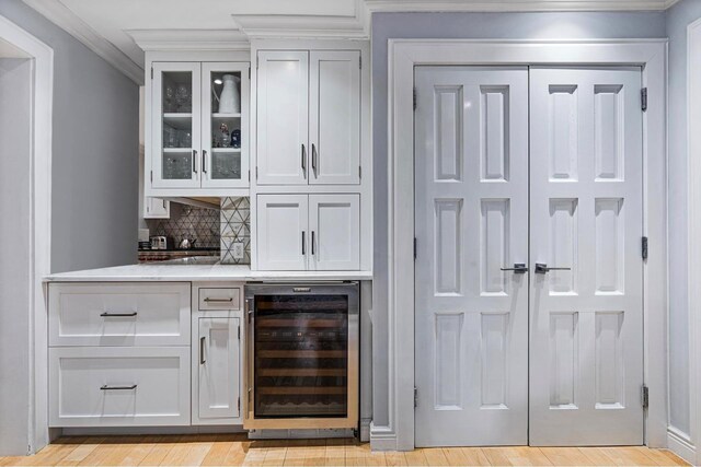 interior space with wine cooler, crown molding, and light hardwood / wood-style flooring