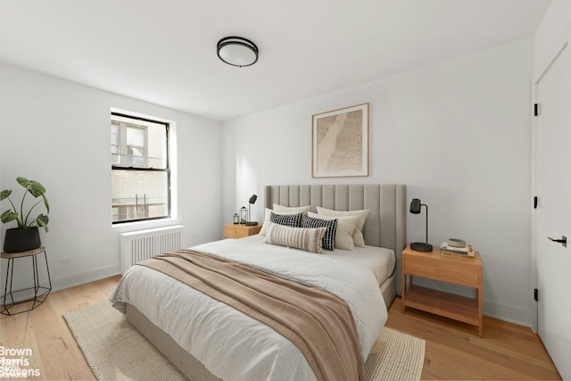 bedroom featuring light wood-style floors, radiator, and baseboards