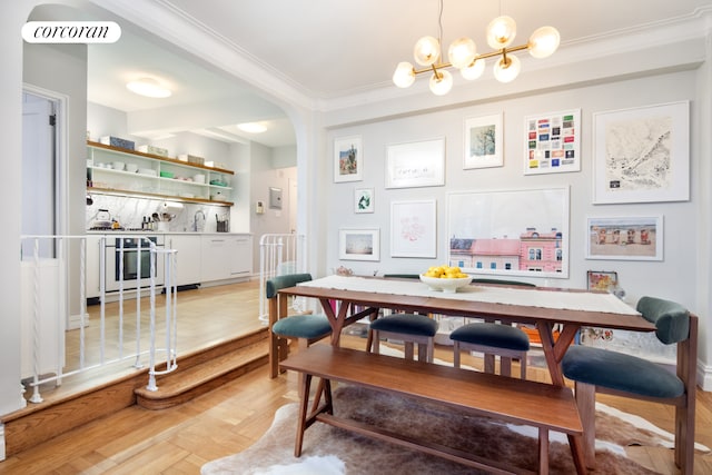 dining room featuring arched walkways, ornamental molding, a dry bar, and a chandelier