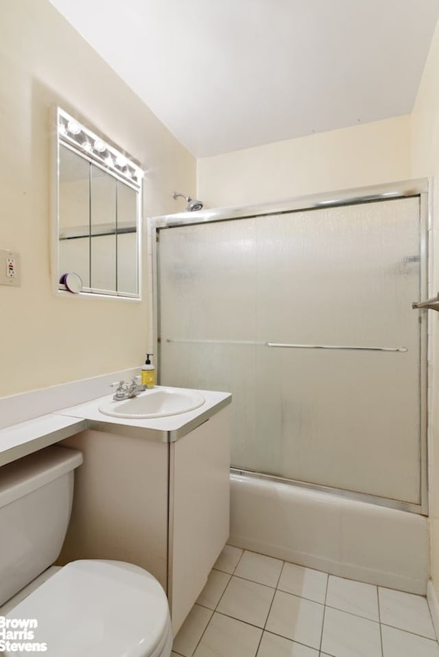 full bath featuring tile patterned flooring, toilet, vanity, and bath / shower combo with glass door