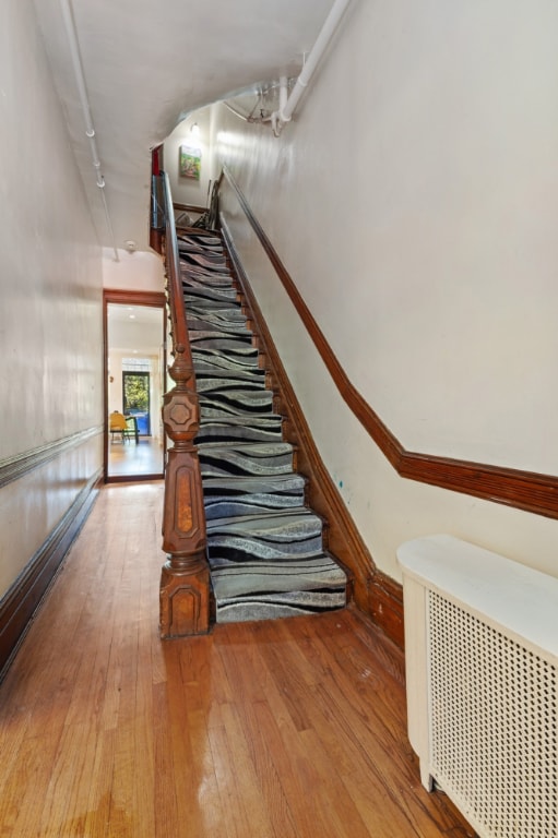 stairs featuring radiator and hardwood / wood-style floors