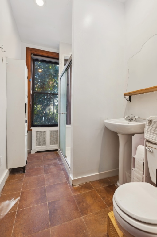 bathroom with toilet, sink, and a shower with shower door