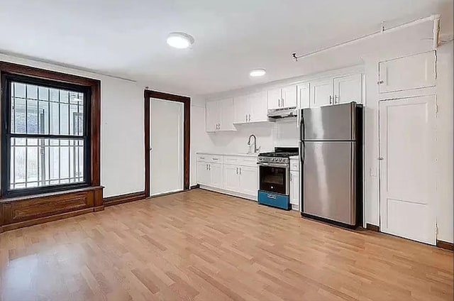 kitchen featuring light wood-type flooring, sink, stainless steel appliances, and white cabinetry