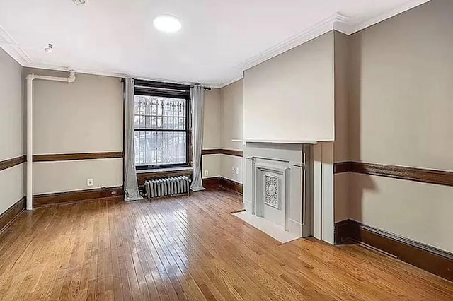 unfurnished living room featuring radiator, ornamental molding, and hardwood / wood-style floors