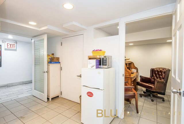 interior space featuring recessed lighting, stainless steel microwave, light tile patterned flooring, and freestanding refrigerator