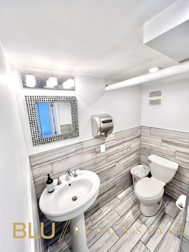 half bath with a wainscoted wall, toilet, and tile walls