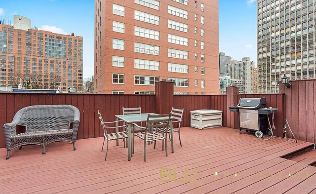 wooden terrace with a city view, outdoor dining space, and a grill