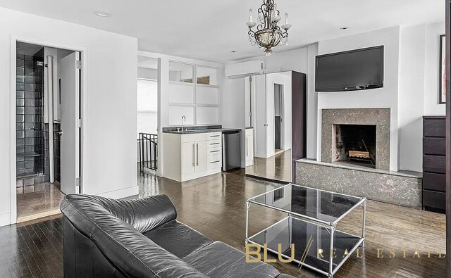 kitchen with dark wood-style flooring, a fireplace, an inviting chandelier, a wall mounted AC, and stainless steel dishwasher