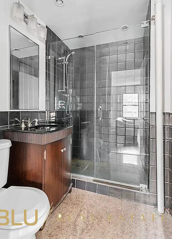 bathroom featuring toilet, a stall shower, vanity, and granite finish floor