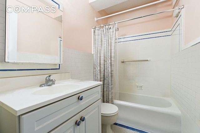 bathroom with toilet, a wainscoted wall, shower / bath combo with shower curtain, vanity, and tile walls