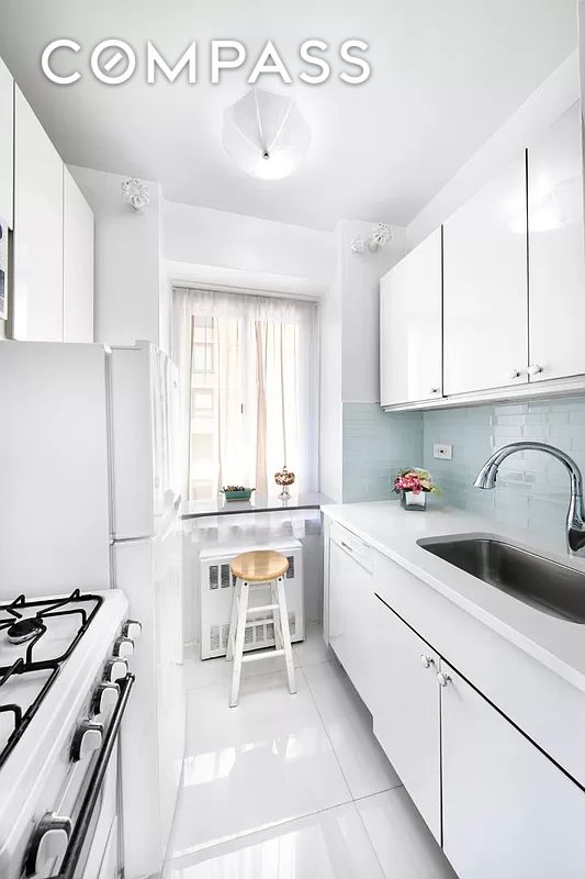 kitchen with a sink, white cabinetry, light countertops, backsplash, and gas range oven