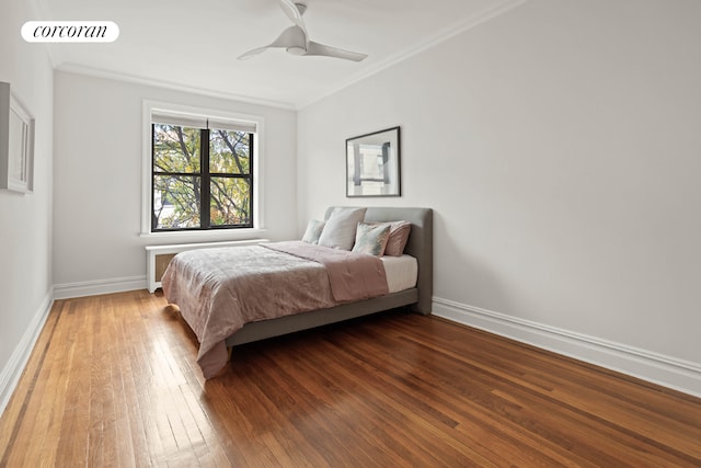 bedroom featuring ornamental molding, visible vents, baseboards, and wood finished floors