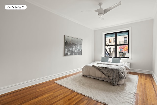 bedroom featuring visible vents, ornamental molding, a ceiling fan, wood finished floors, and baseboards