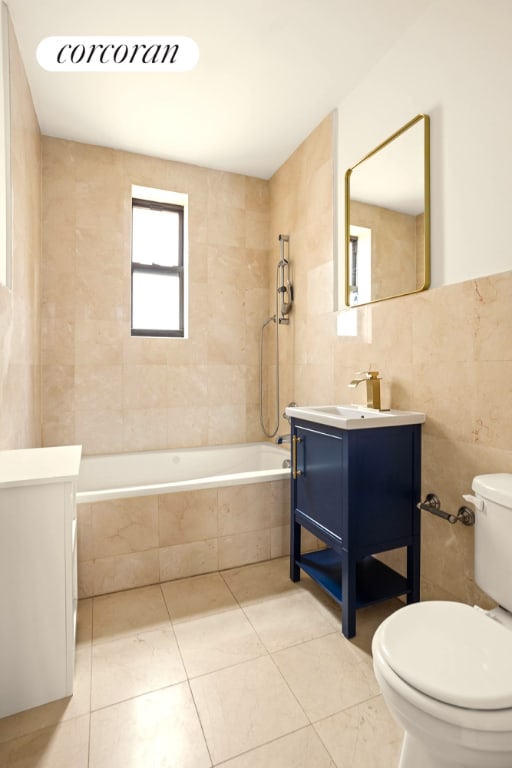 full bath featuring tile walls, toilet, tiled shower / bath combo, vanity, and tile patterned floors