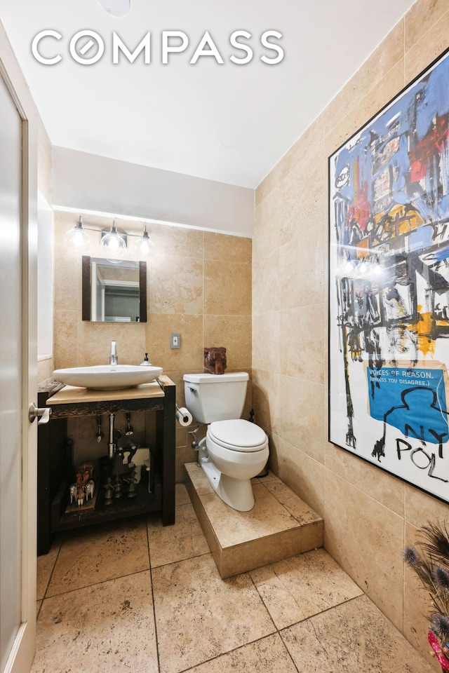 half bath with toilet, tile walls, and vanity