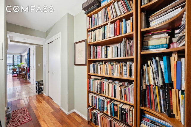 corridor with baseboards and wood finished floors