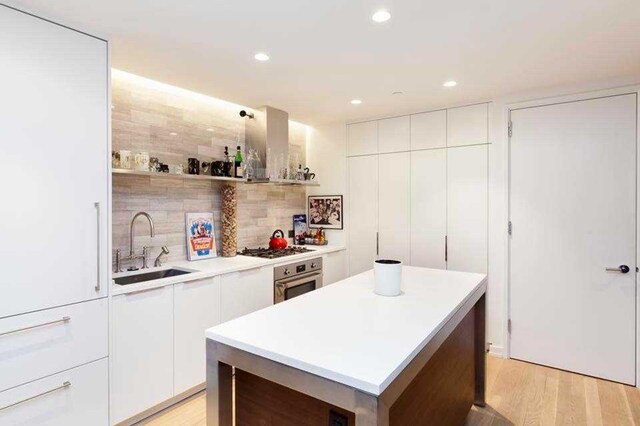 234 E 23rd St Unit 4-A, New York City, NY 10010 - kitchen featuring appliances with stainless steel finishes, a sink, island range hood, modern cabinets, and white cabinets