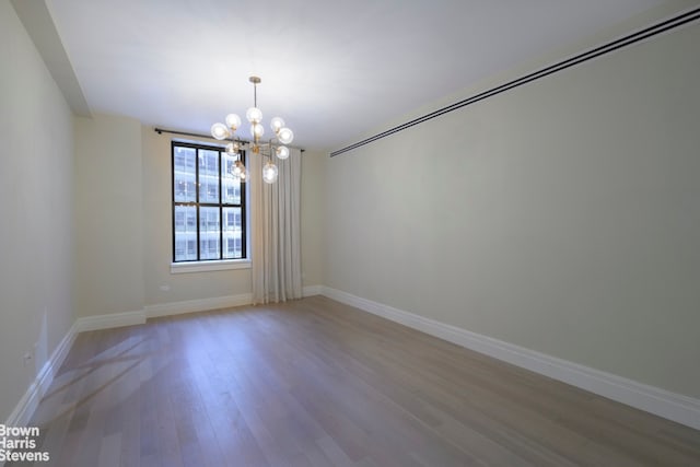 unfurnished room featuring a chandelier and wood-type flooring