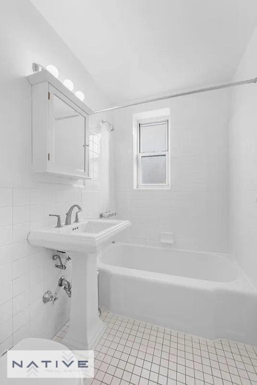 bathroom featuring tile patterned floors, toilet, tiled shower / bath combo, and tile walls