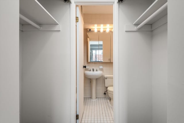 half bathroom featuring toilet, tile walls, and tile patterned flooring