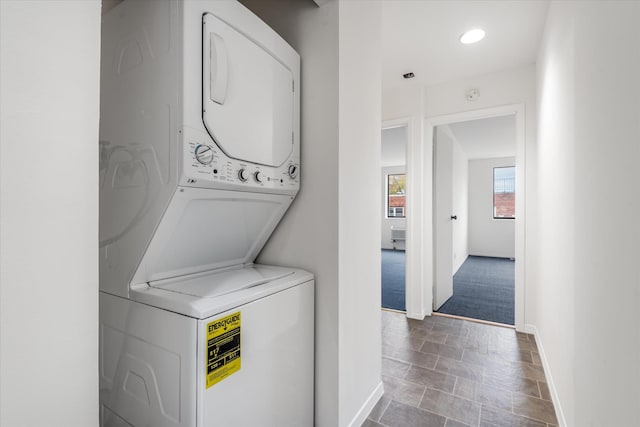 washroom featuring laundry area, stacked washer / dryer, and baseboards