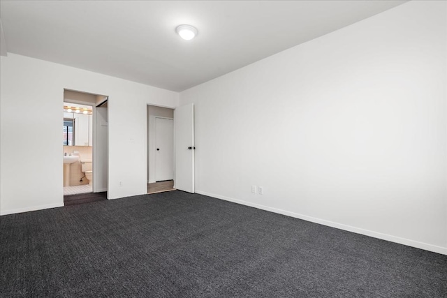 unfurnished bedroom with dark carpet and ensuite bath