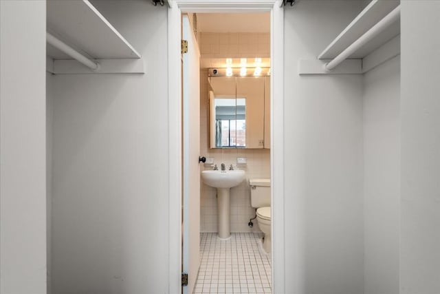 bathroom featuring tile walls, tile patterned floors, and toilet