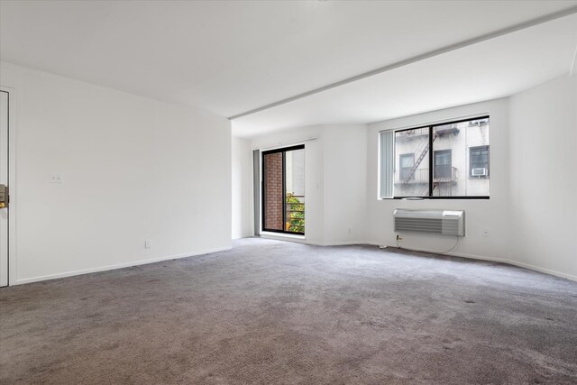 unfurnished room with a wall unit AC, carpet flooring, and baseboards