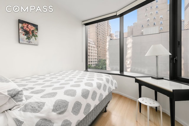 bedroom featuring a view of city and wood finished floors