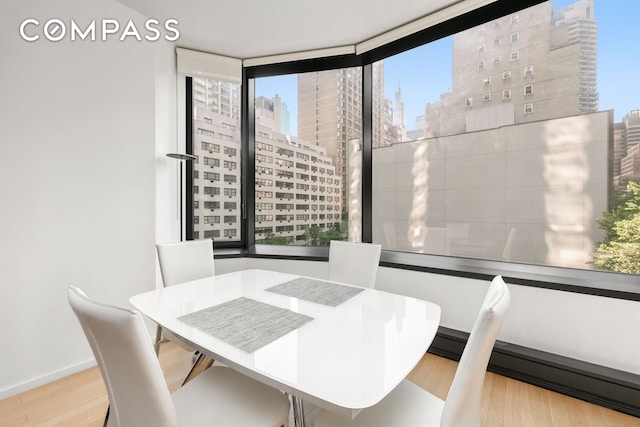 dining space with a city view, light wood-style floors, and baseboards