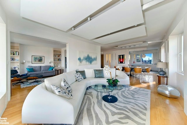 living room featuring built in features and light hardwood / wood-style flooring